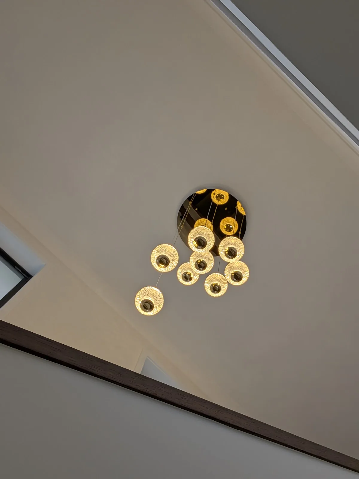 Looking up at eight glowing glass pendant globes under a mirrored gold canopy