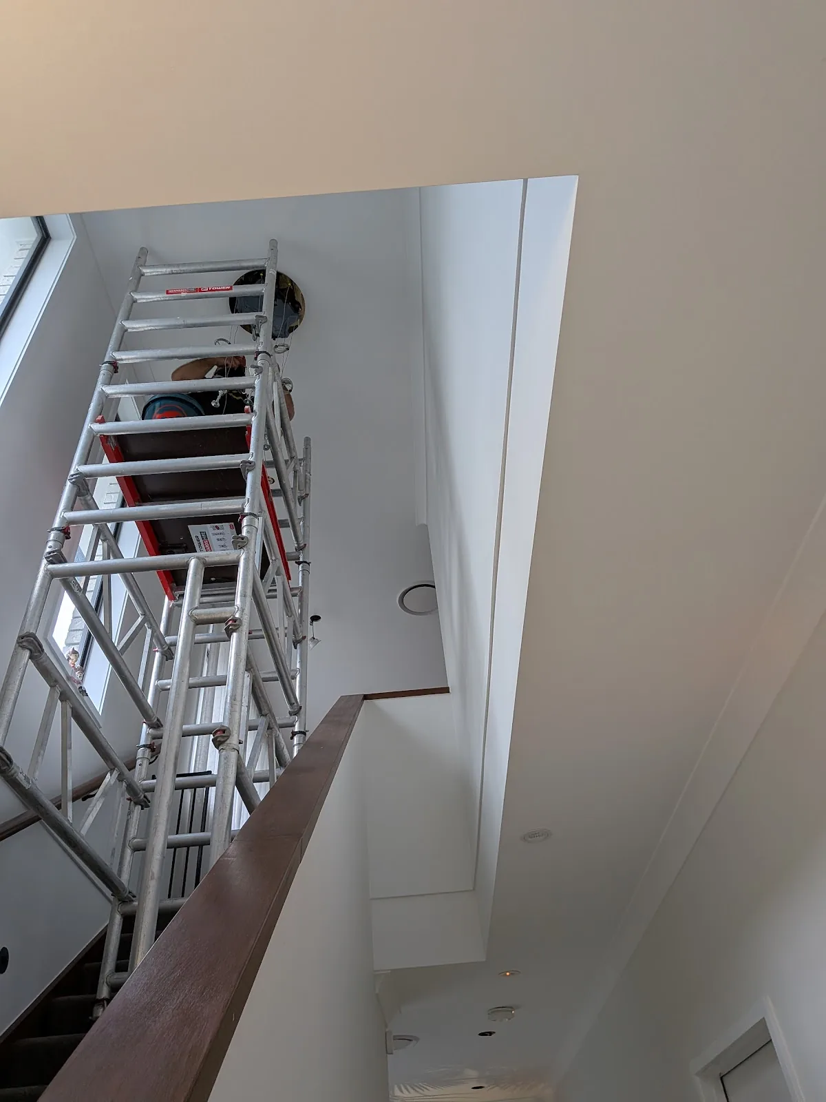 Scaffold tower set up in a two-storey stairwell for a high ceiling light install