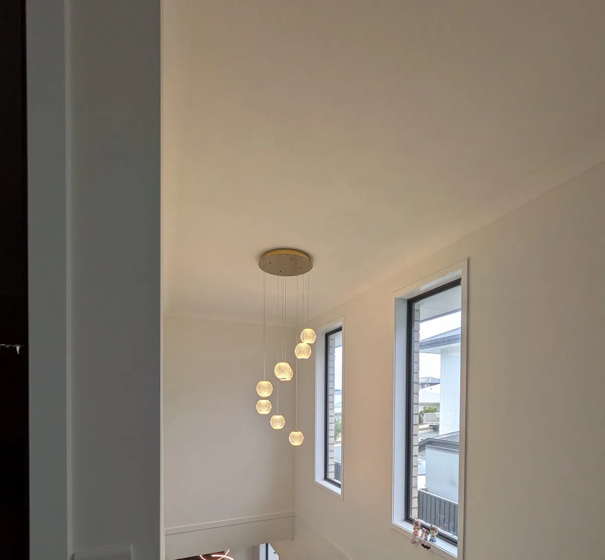 Pendant cascade hanging in a double-height void beside tall windows