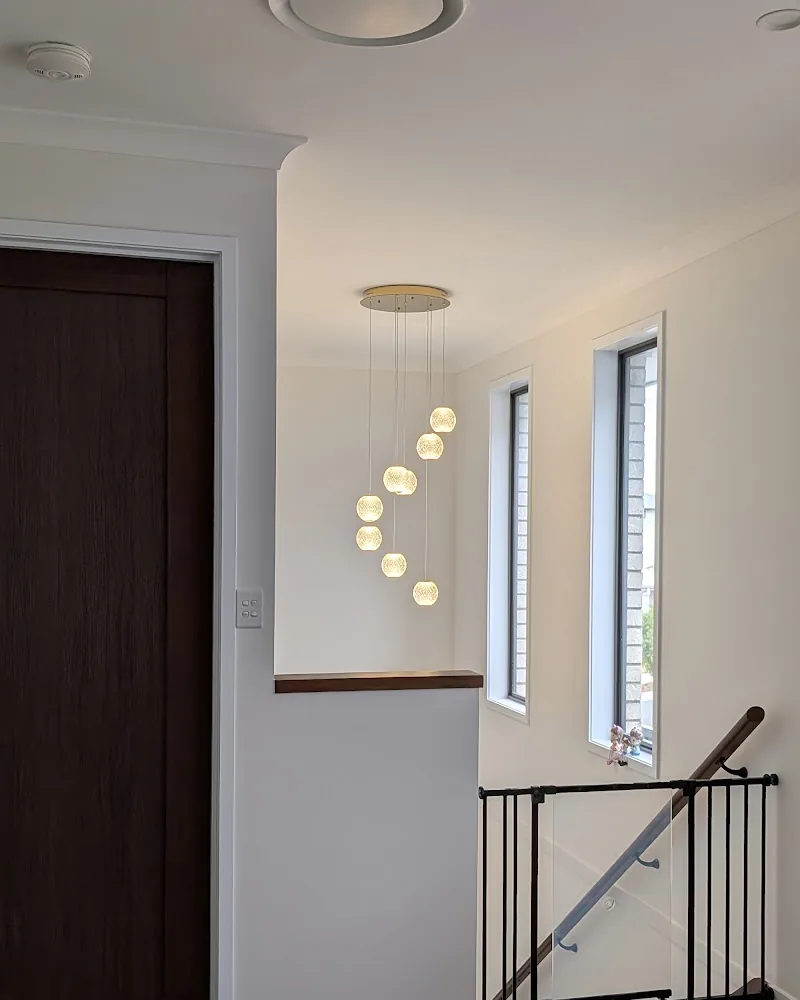 Multi-drop glass pendant light glowing over a two-storey stairwell, installed by RF Electrical Services